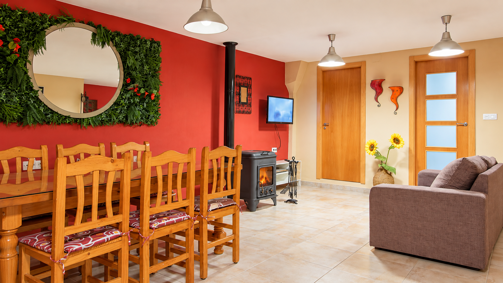 Salón-comedor de Casa Rural Bekirent en alquiler integro en Bocairent, Valencia, con mesa de madera, estufa de leña, sofá y decoración acogedora.