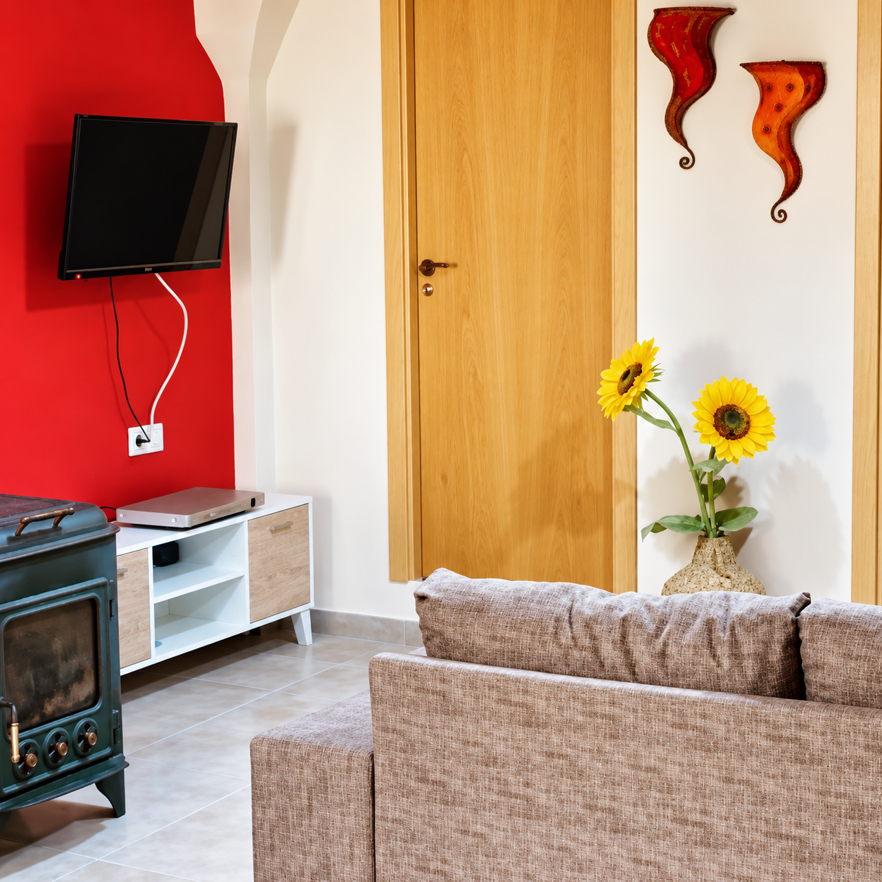 Salón de Casa Rural Bekirent en Bocairent, Valencia, con sofá, estufa de leña, televisión y decoración con girasoles.